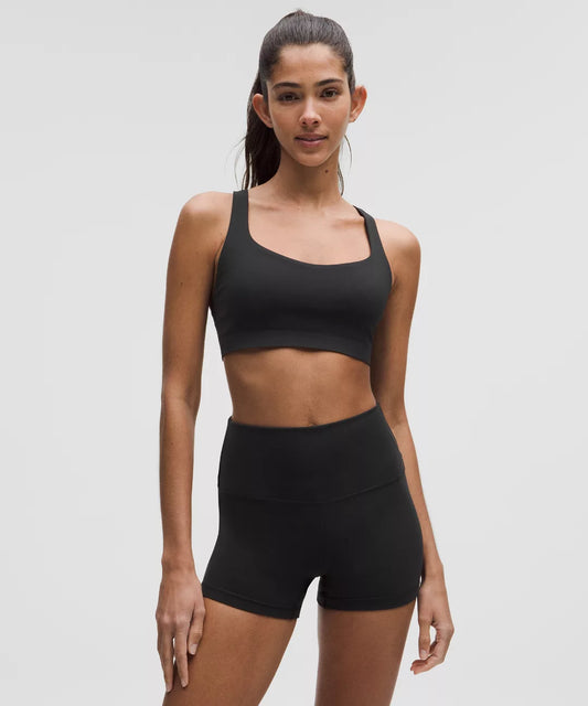 Woman wearing a black sports bra and shorts on a gray background