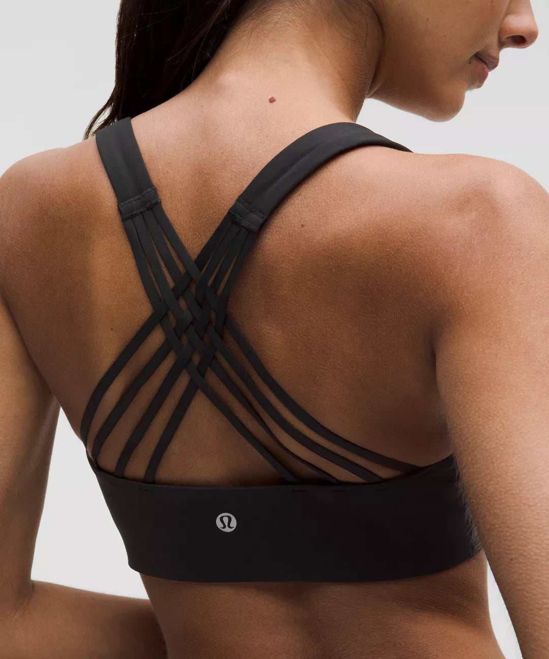 Black sports bra with criss-cross straps worn by a person on a neutral background