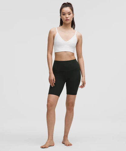 Woman wearing a white sports bra and black shorts on a plain background