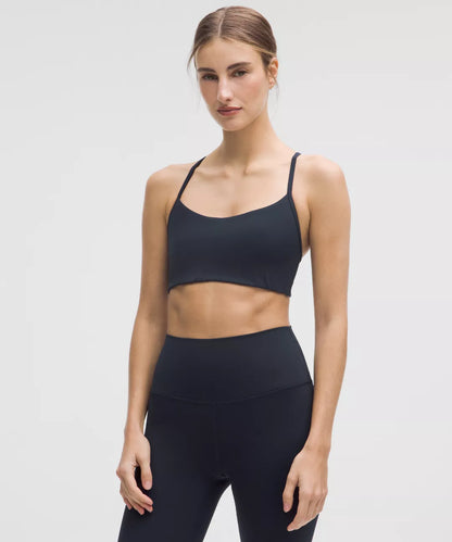 Woman wearing a black sports bra and leggings on a light gray background