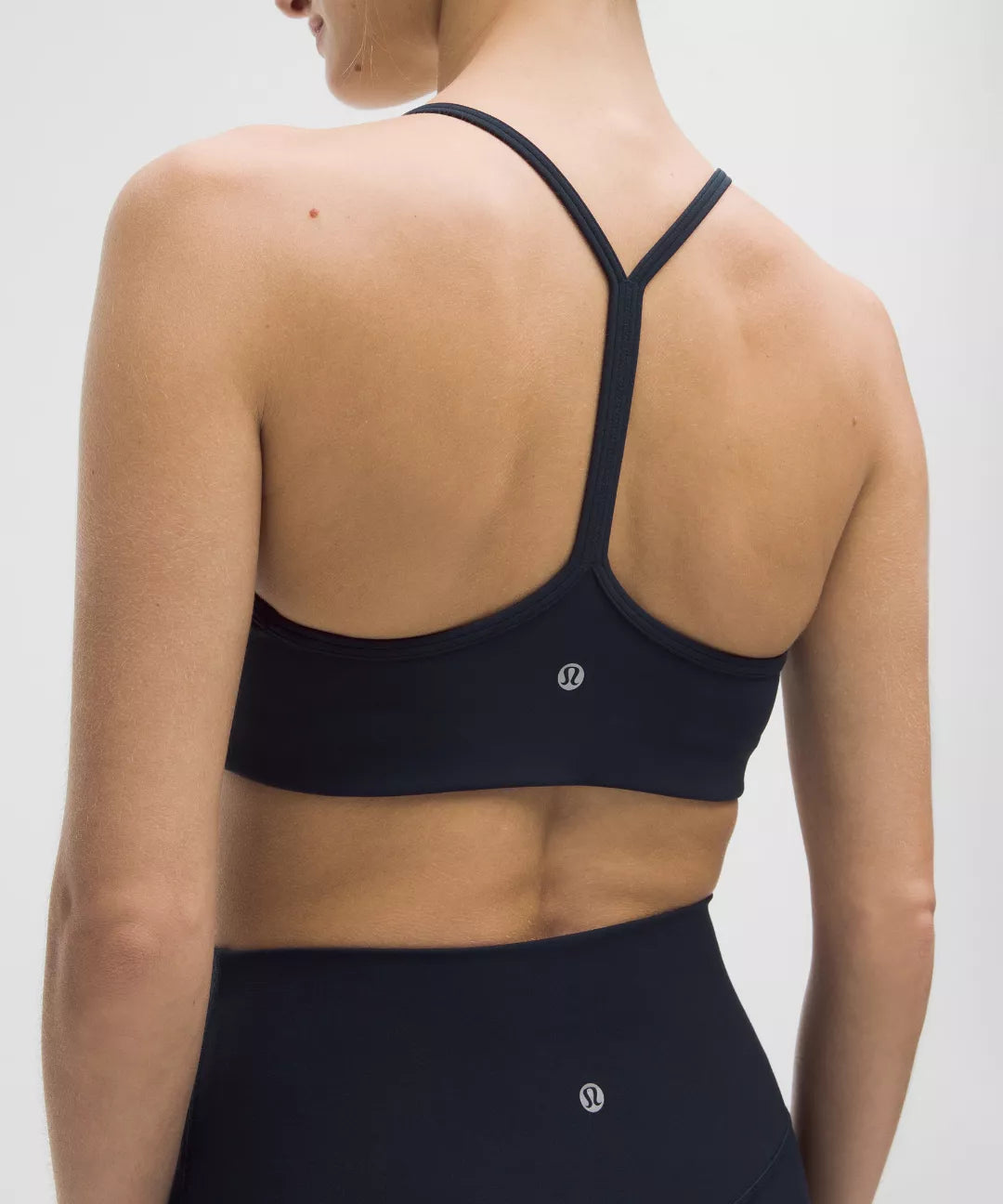 Black sports bra with thin straps worn by a person on a plain background