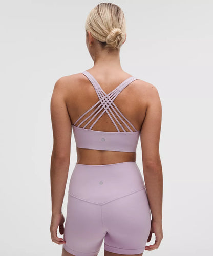 Woman wearing a light purple sports bra and shorts set on a plain background
