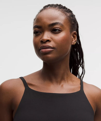 Woman wearing a black tank top against a plain background