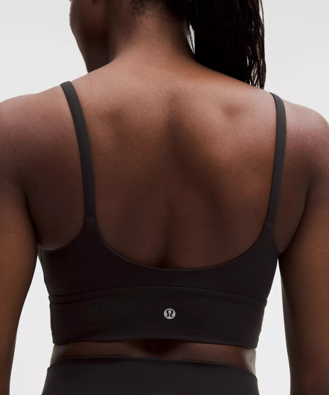 Black sports bra worn by a person on a light gray background