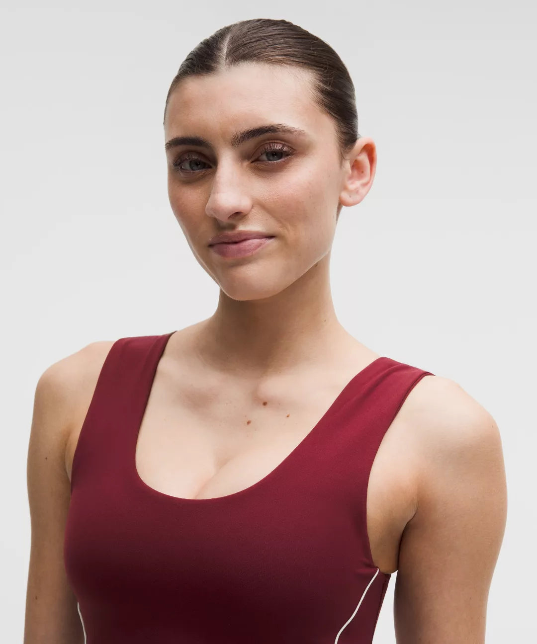 Woman wearing a maroon sleeveless top against a plain background