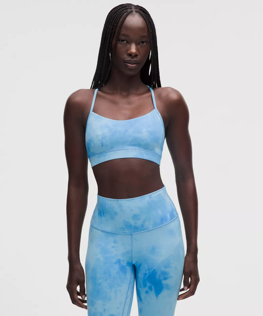 Woman wearing a blue tie-dye sports bra and leggings set on a light gray background