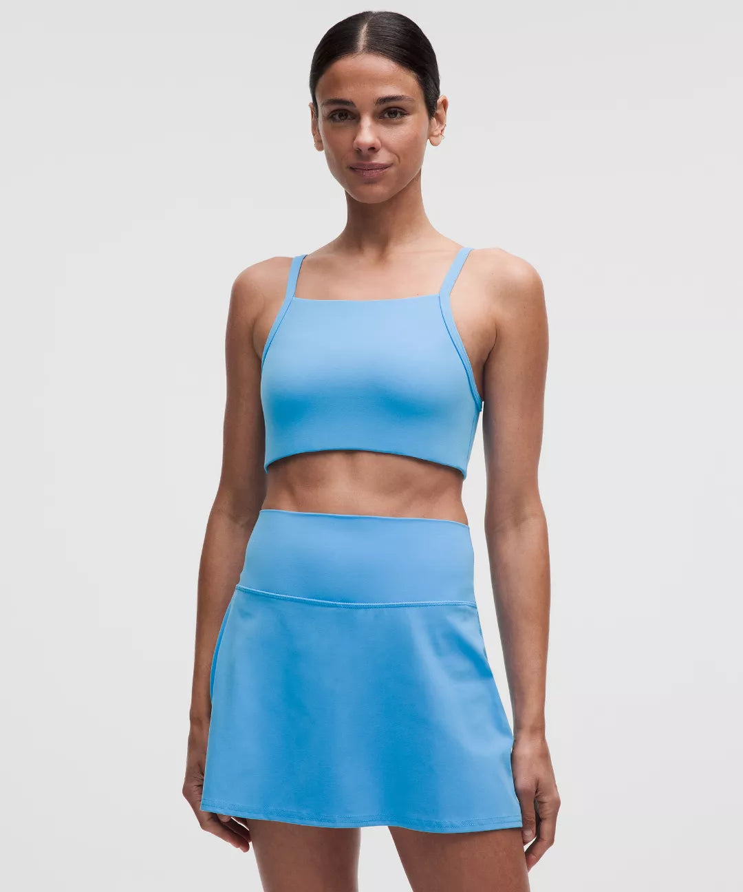 Woman wearing a blue athletic top and skirt on a light gray background