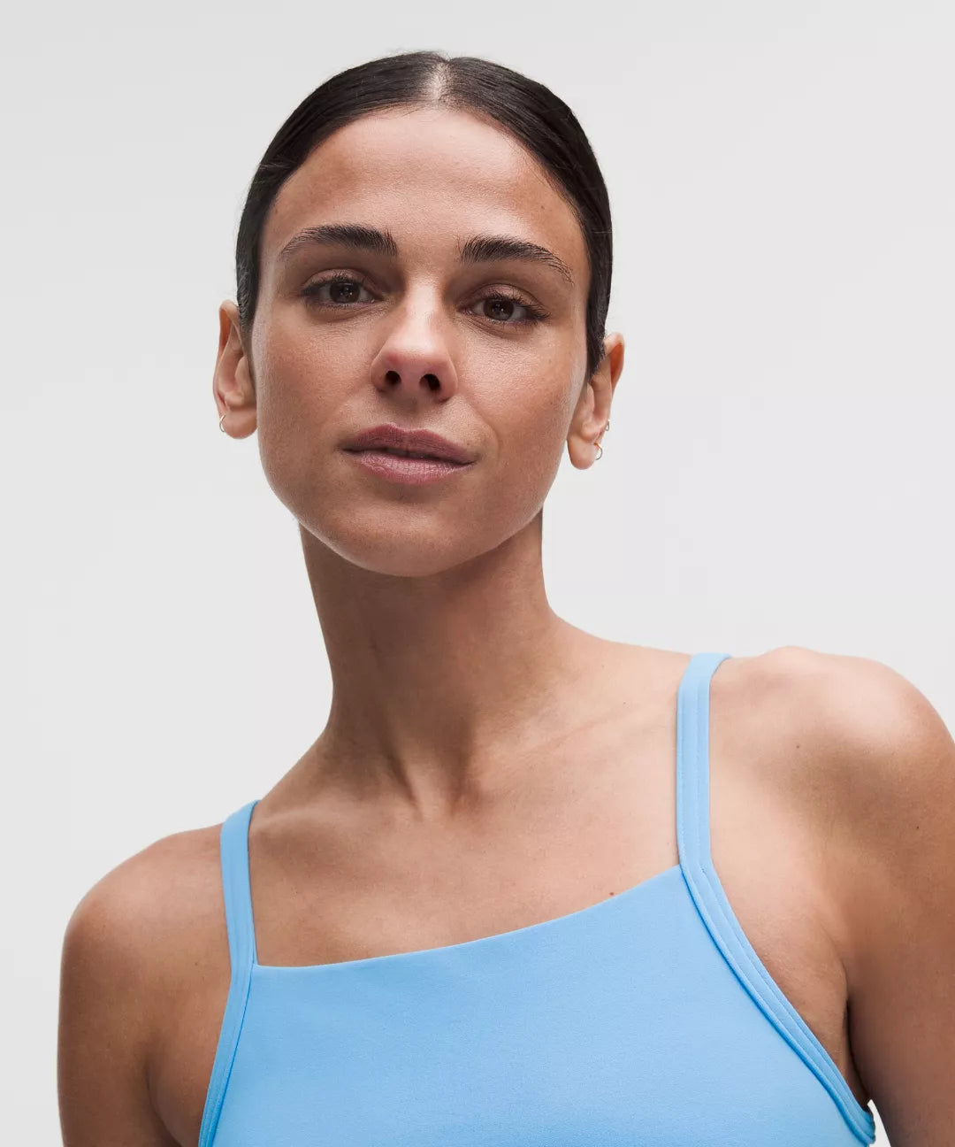 Woman wearing a light blue tank top against a plain background