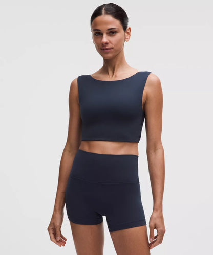 Woman wearing a navy blue athletic outfit on a light gray background