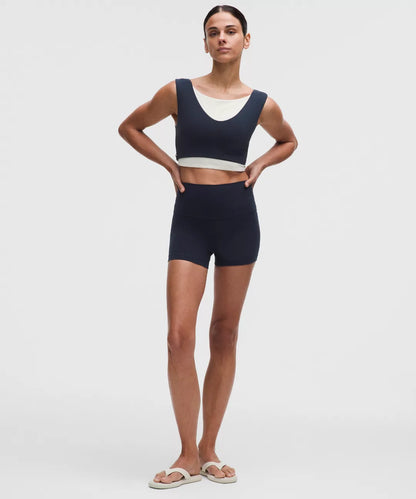 Woman wearing a navy blue sports bra and shorts set on a white background