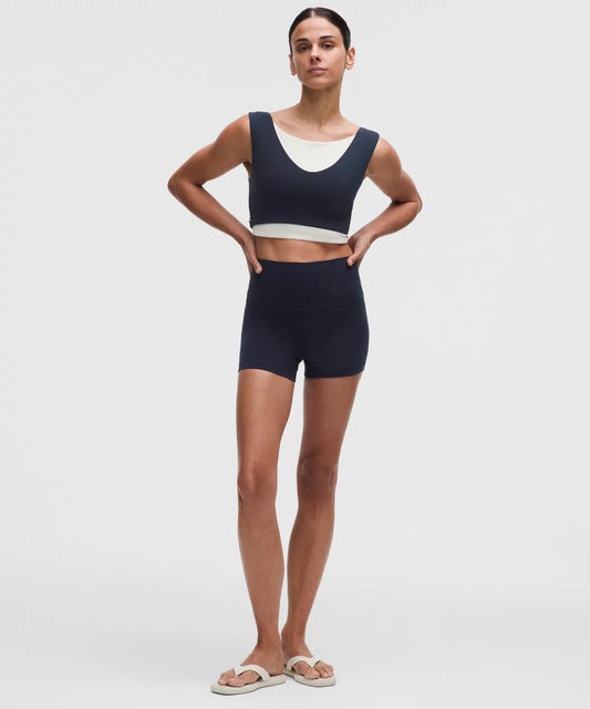 Woman wearing a navy blue sports bra and shorts set on a white background