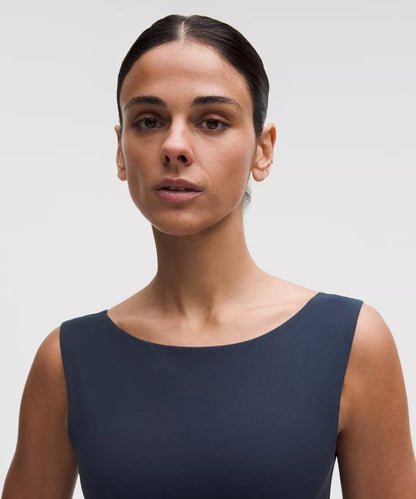 Woman wearing a navy blue sleeveless top against a plain background