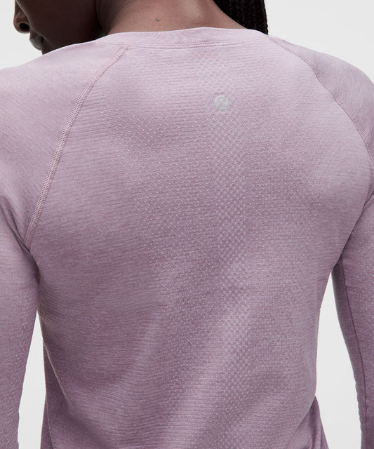 Close-up of a person wearing a purple long-sleeve athletic shirt on a light gray background