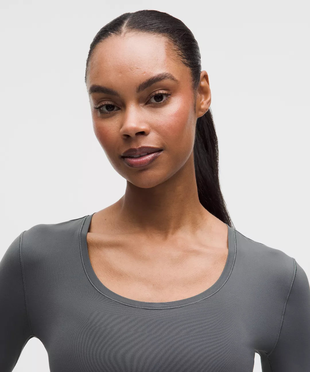 Woman wearing a gray athletic top against a plain background