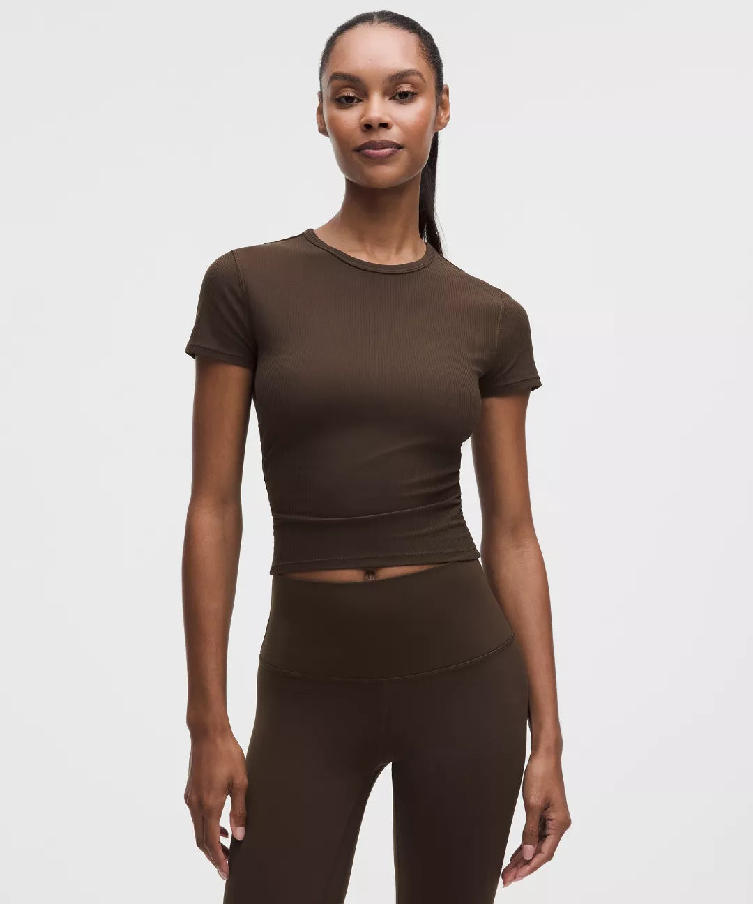 Woman wearing a brown athletic outfit on a white background