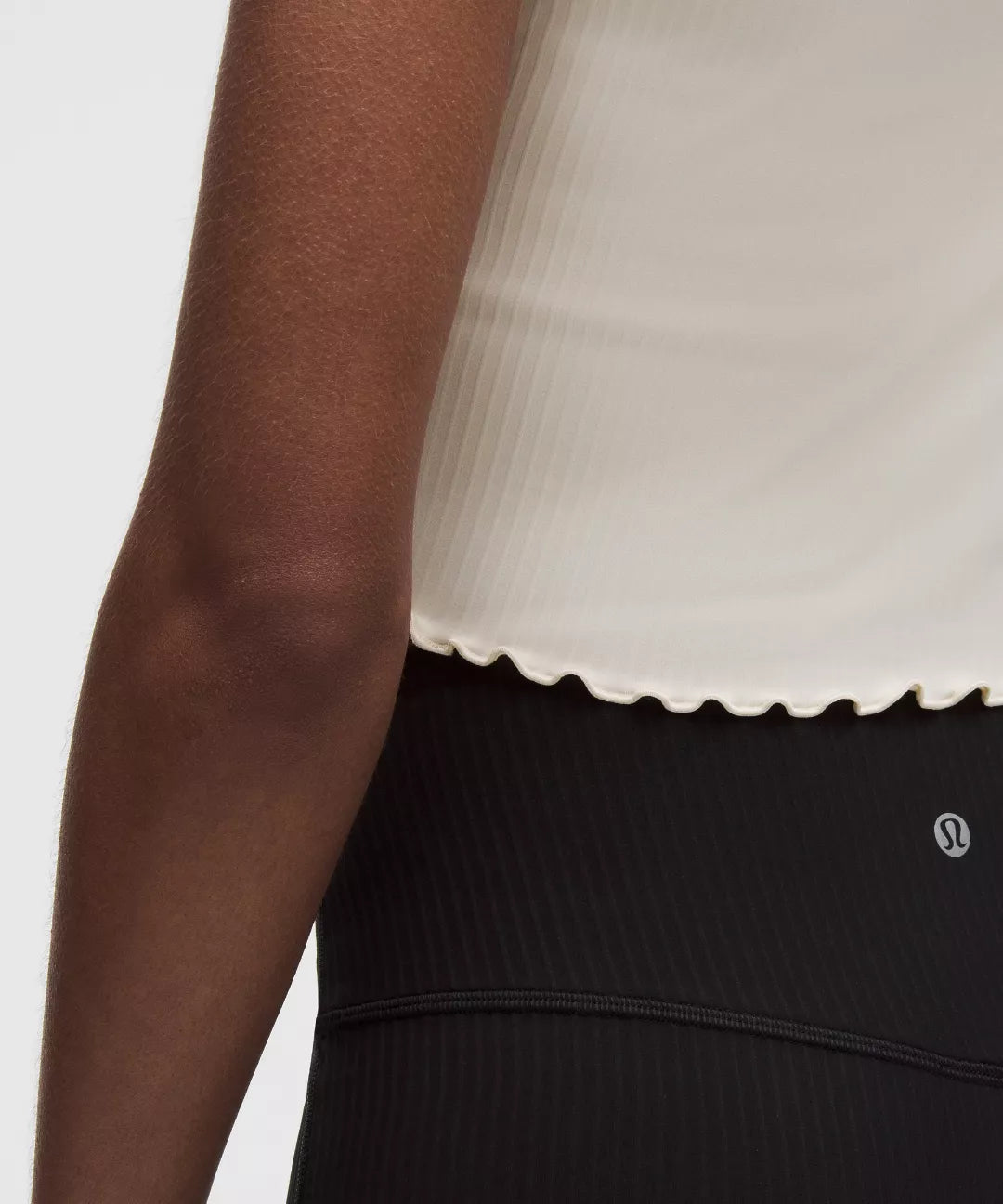 Person wearing a white top and black leggings with a visible brand logo on a light gray background
