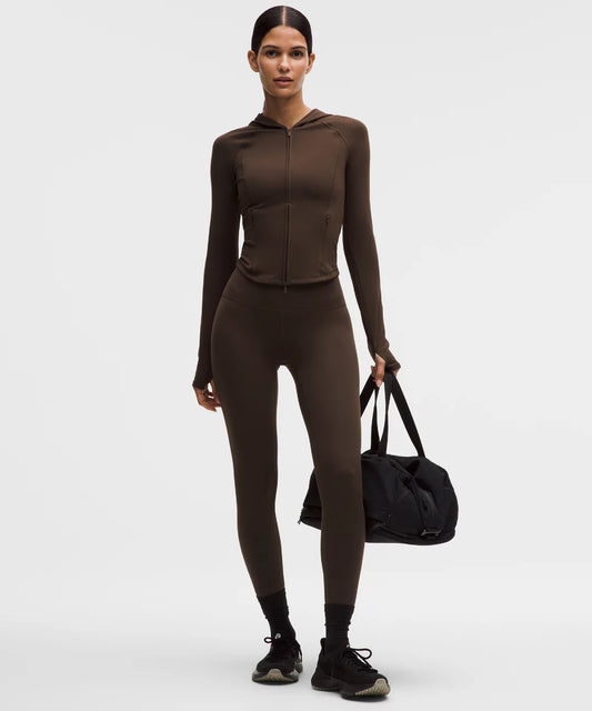 Person wearing a brown athletic outfit holding a black duffel bag on a white background