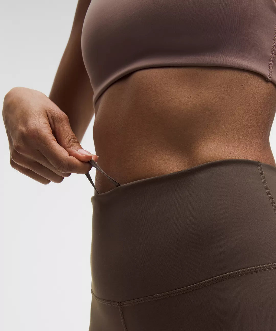 Person wearing a brown sports bra and leggings against a light background