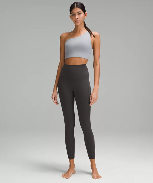 Woman wearing a gray sports bra and black leggings on a gray background