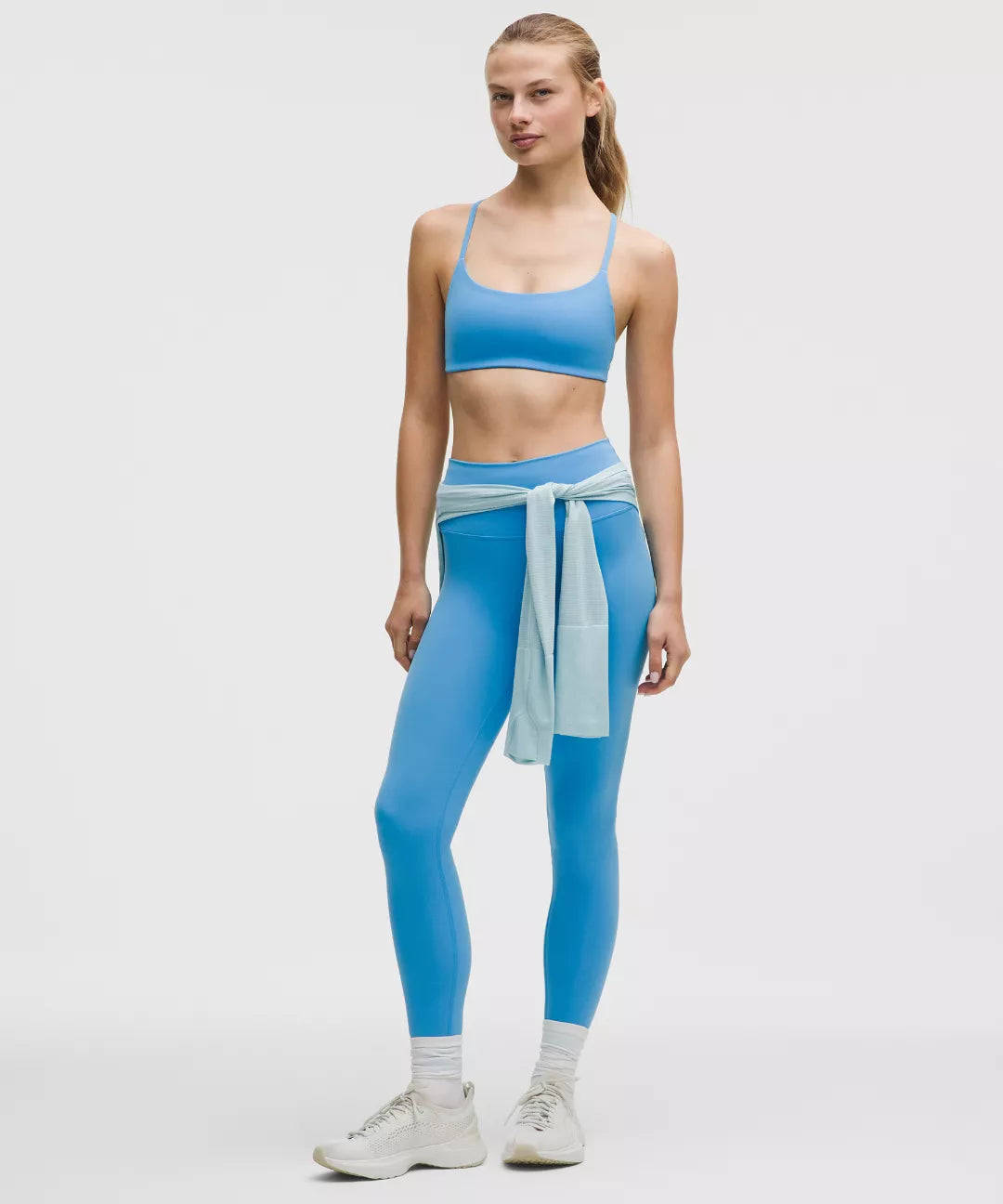 Woman wearing a blue athletic outfit with a white background