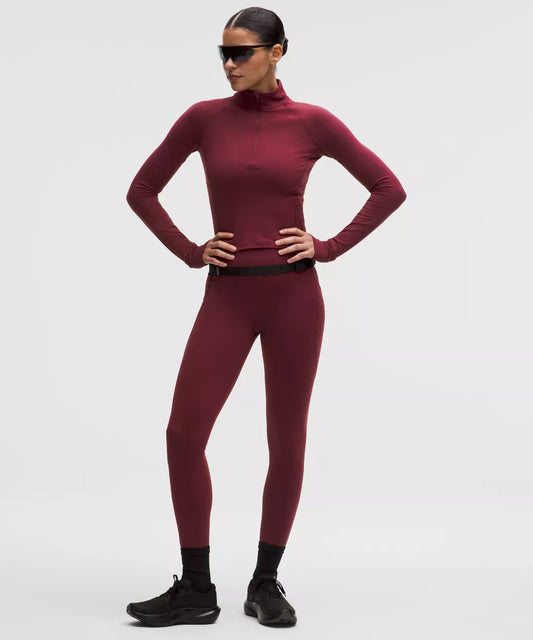 Person wearing a maroon turtleneck and leggings set on a light gray background