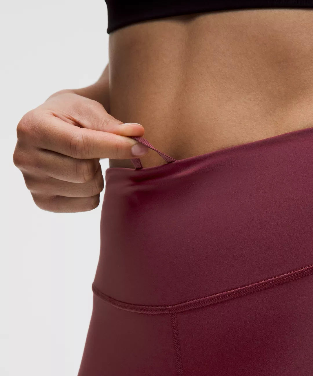 Person adjusting a maroon athletic outfit against a neutral background