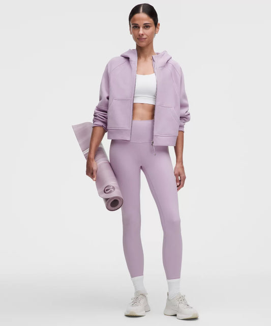 Woman in lavender athletic wear holding a yoga mat on a white background