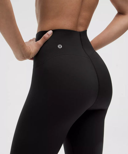 Person wearing black leggings with a visible brand logo on a light gray background