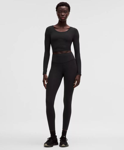 Person wearing a black long-sleeve top and leggings on a white background