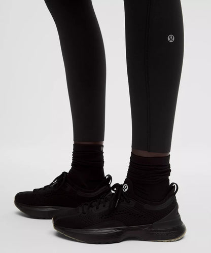 Black leggings with a brand logo worn by a person on a light gray background