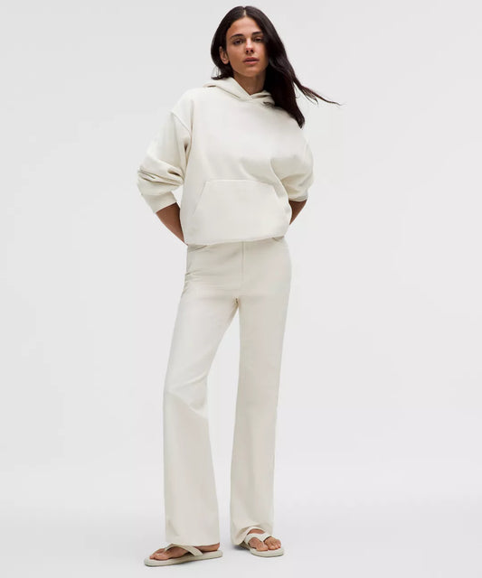 Woman wearing a white hoodie and pants on a plain background