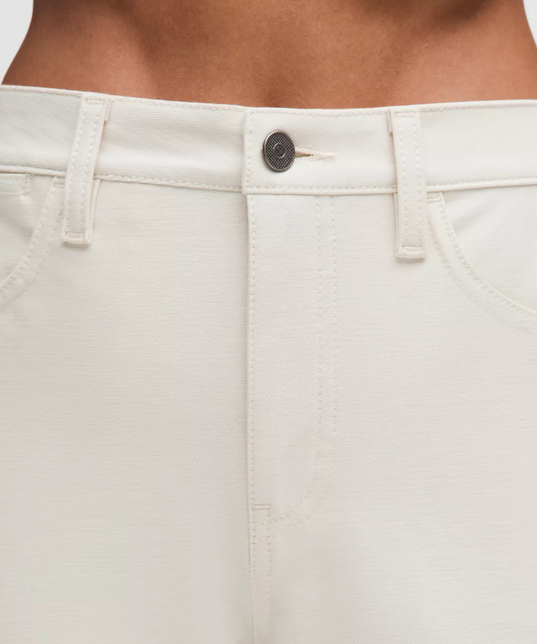 Close-up of beige pants with a button on a neutral background