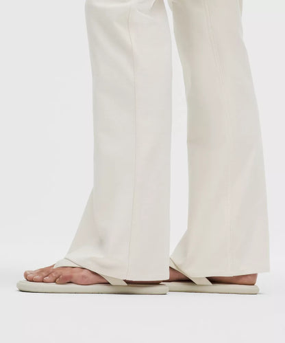 Person wearing white sandals and pants on a plain background