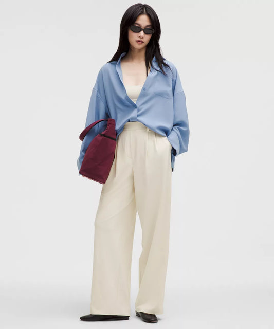 Person wearing a light blue shirt, beige pants, and dark sunglasses on a white background