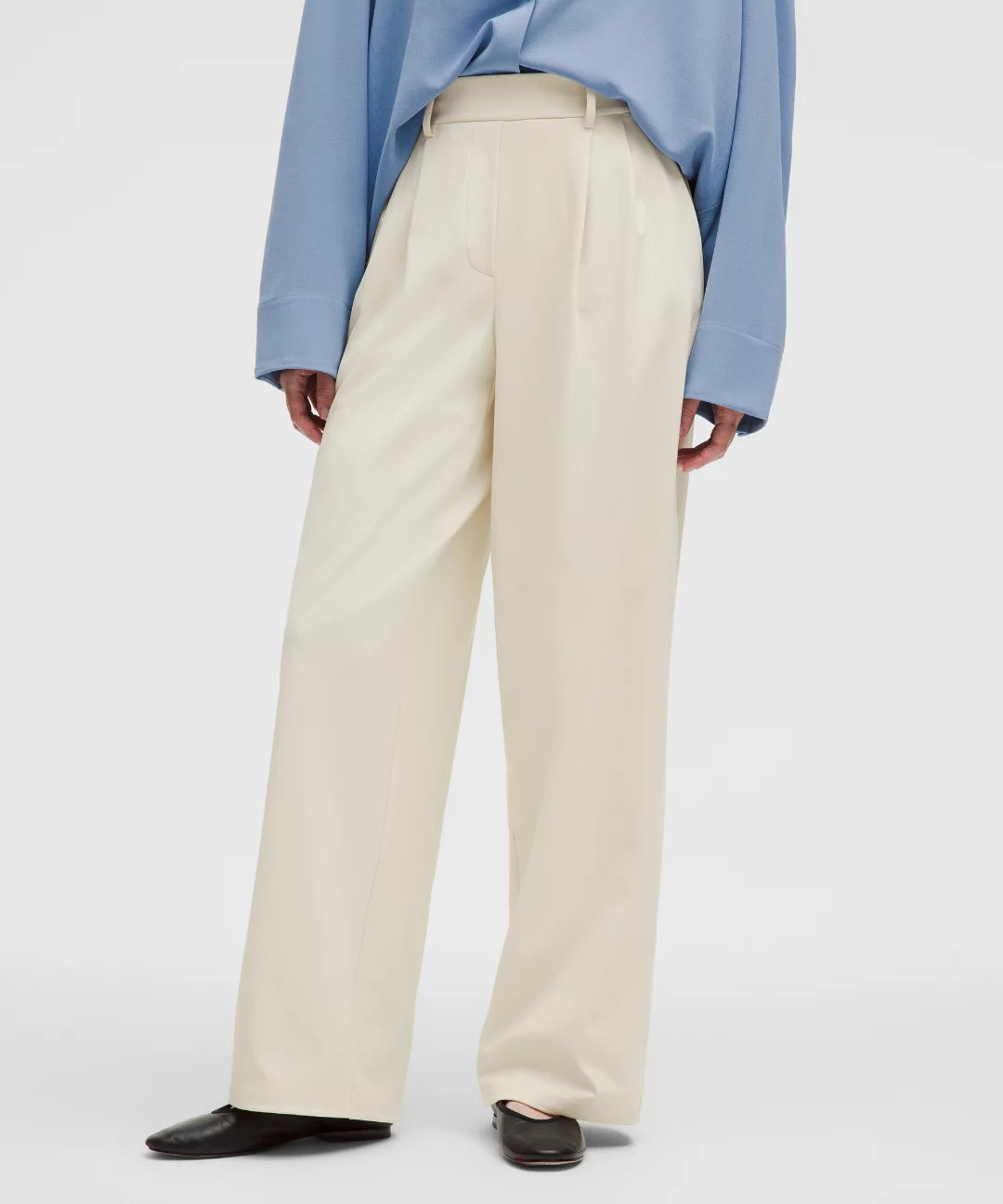 Person wearing light beige pants and a blue shirt on a white background