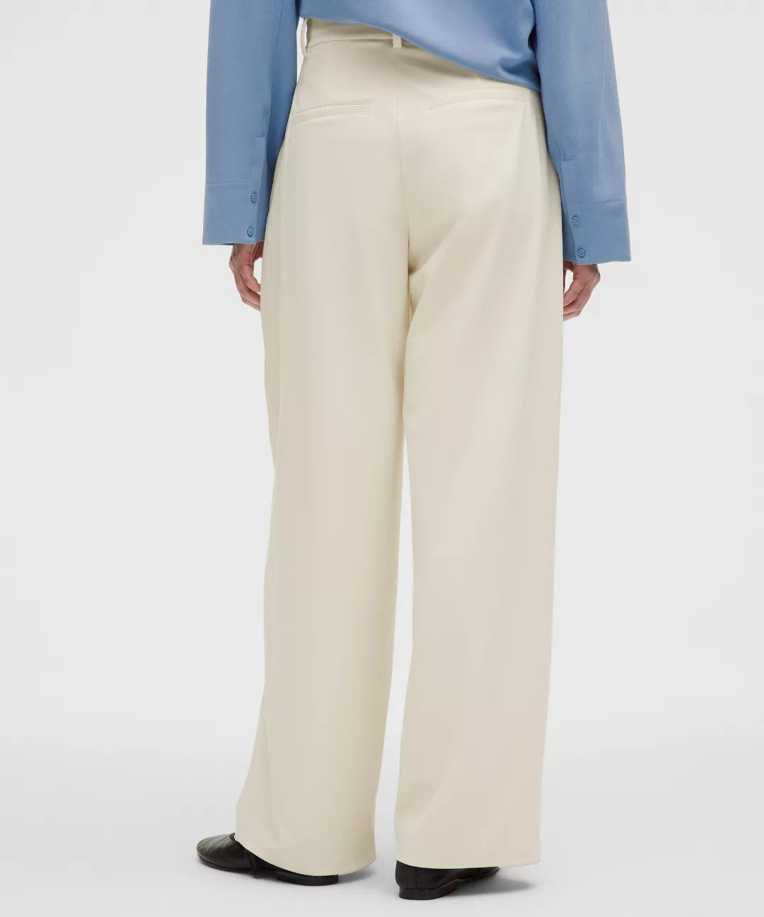 Person wearing beige pants with a light blue jacket on a white background