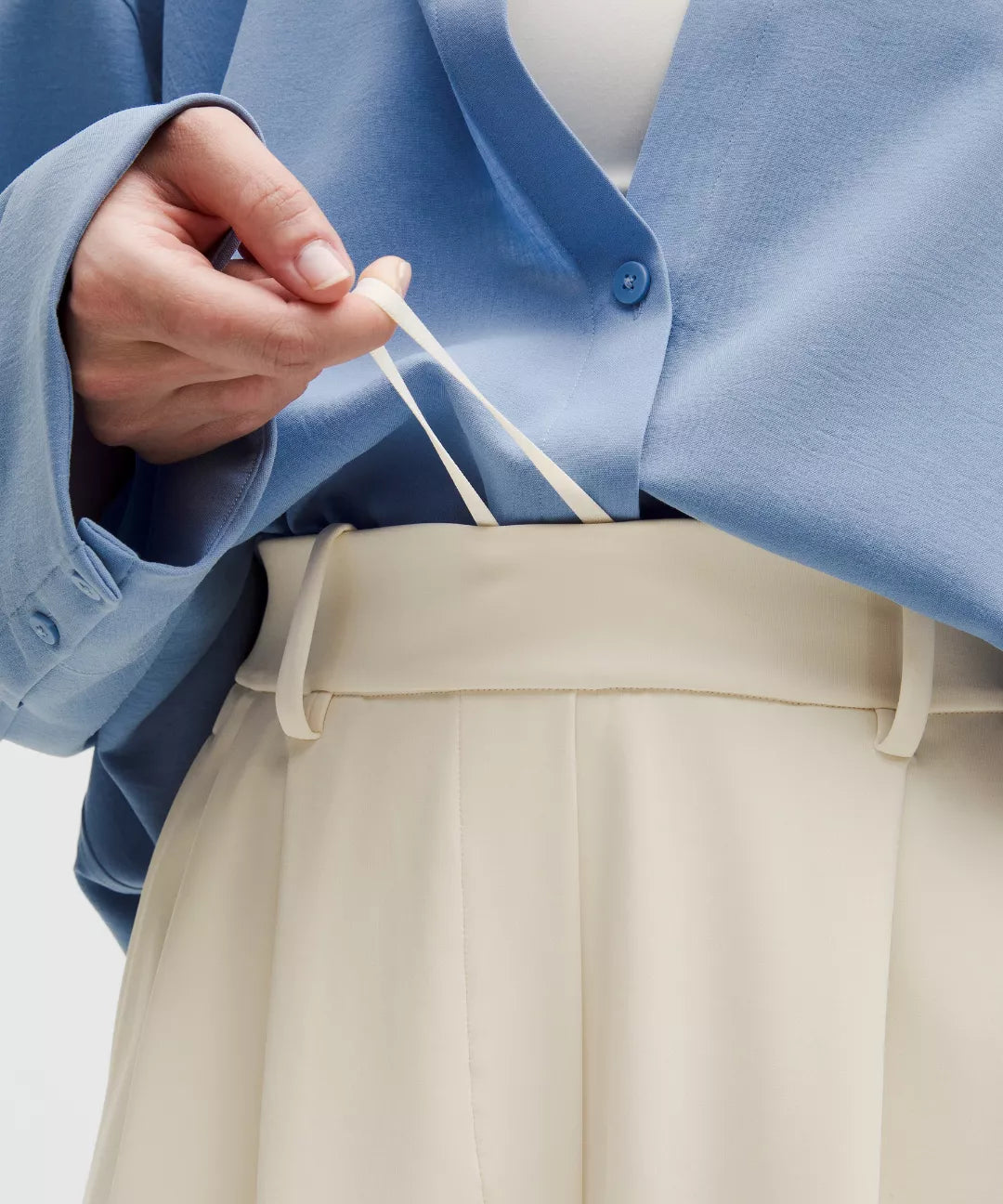 Person wearing a blue jacket and beige pants holding a white string.