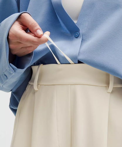 Person wearing a blue jacket and beige pants holding a white string.
