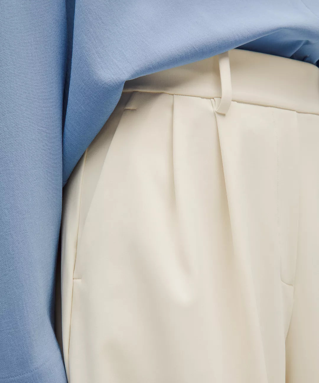 Close-up of beige pants with a blue background