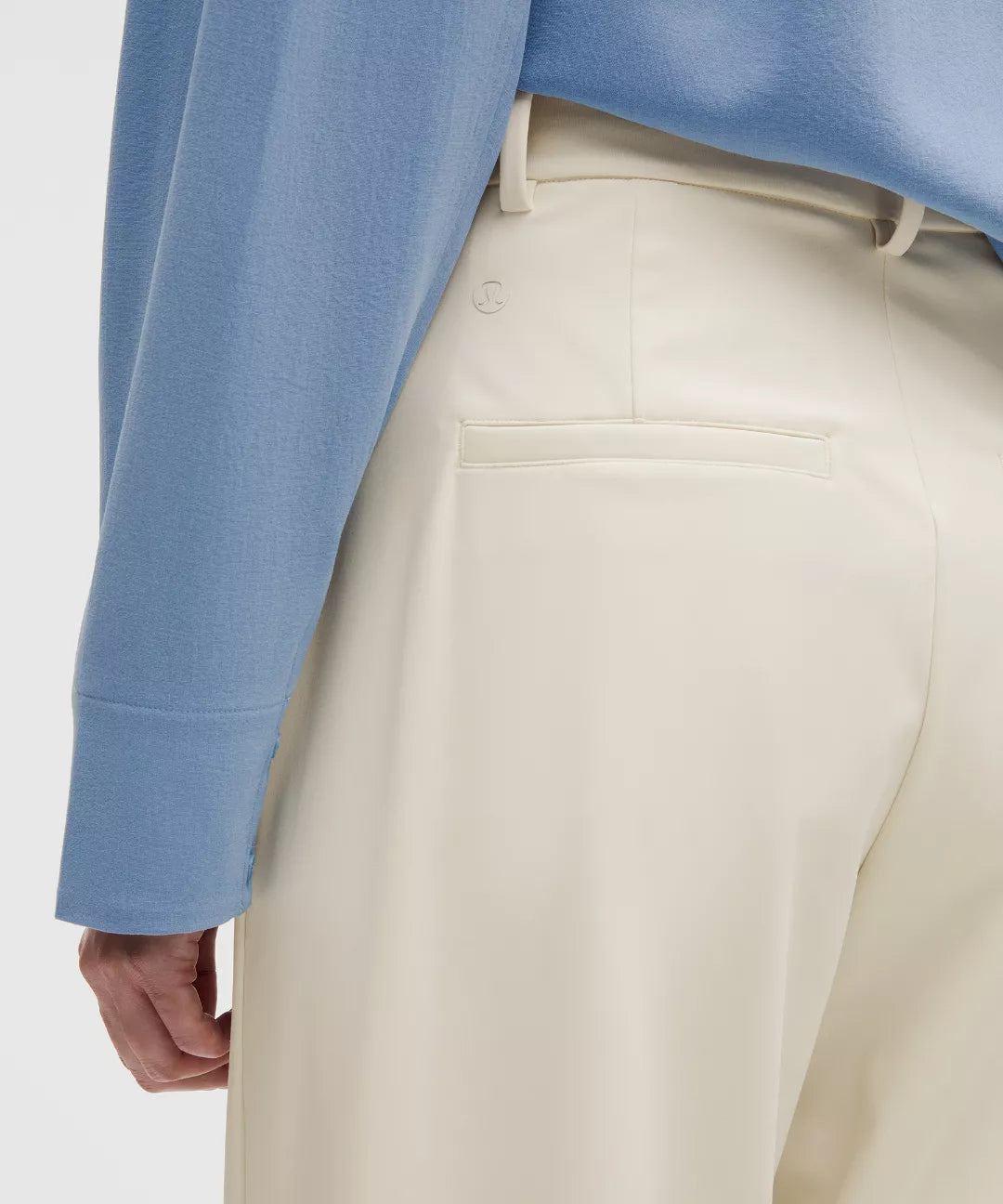 Close-up of beige pants with a blue sweater sleeve in the background
