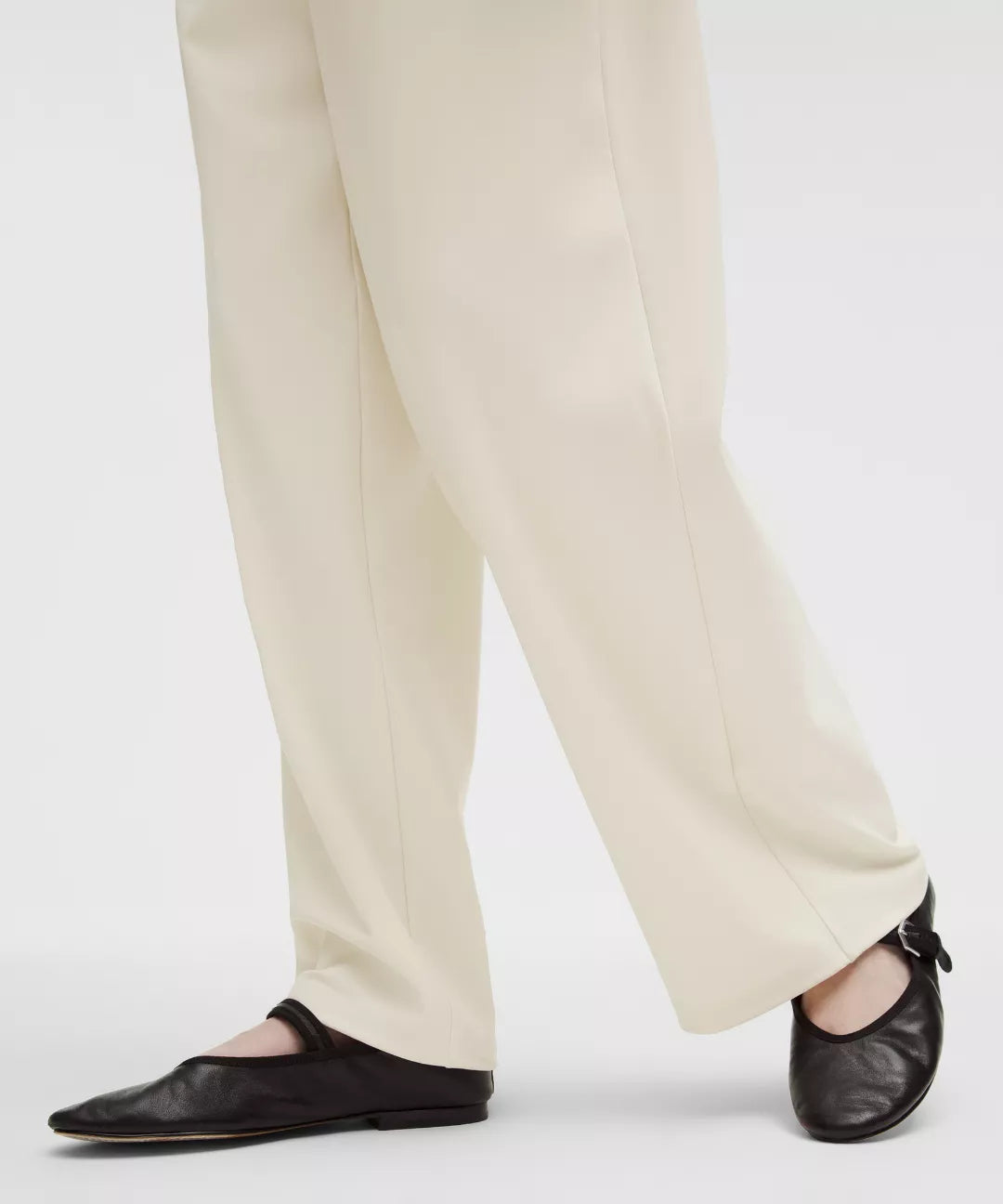 Person wearing beige pants and black shoes on a white background