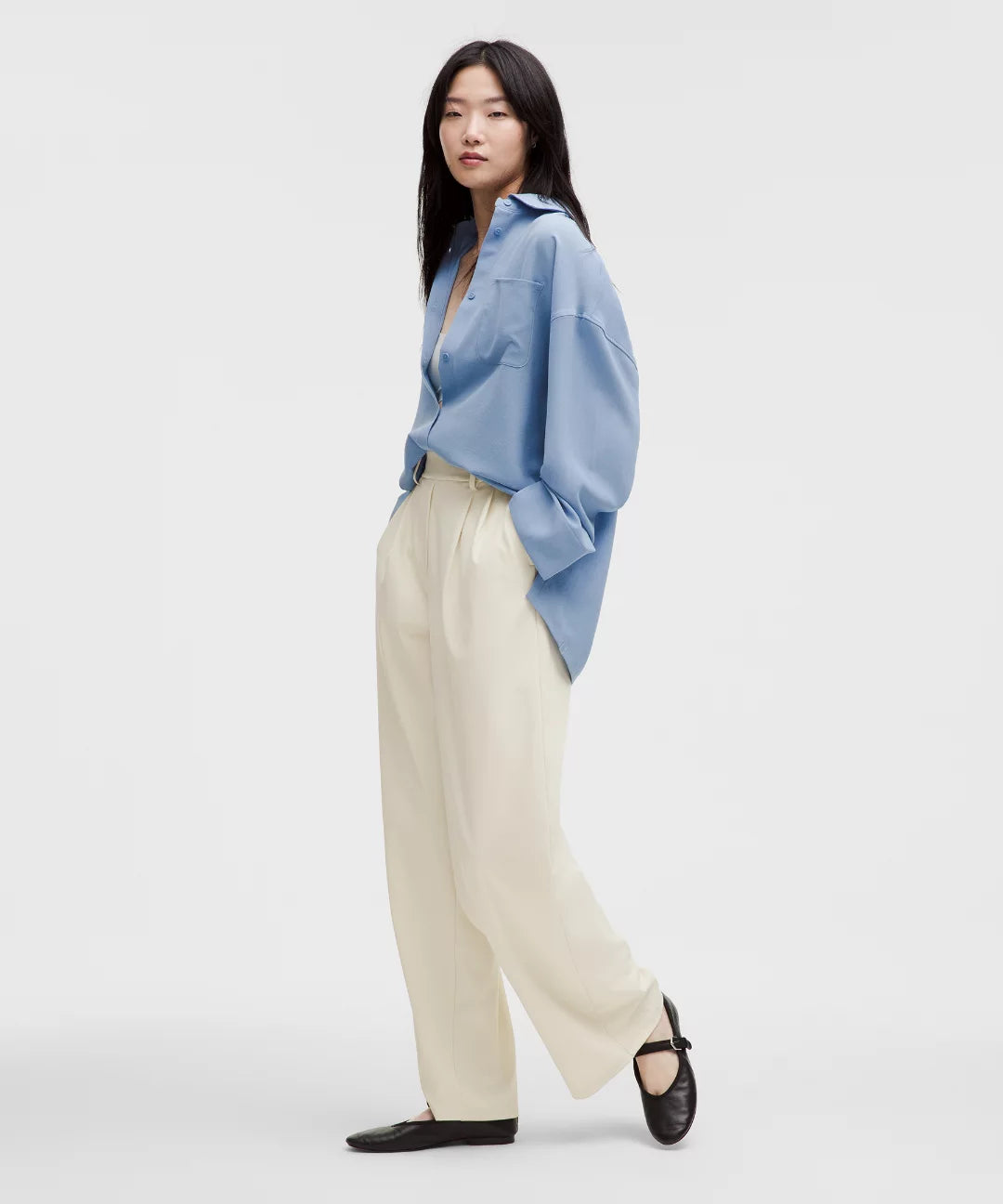 Woman wearing a light blue shirt and beige pants on a white background