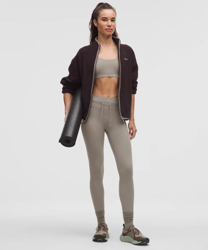 Woman in athletic wear holding a yoga mat on a white background