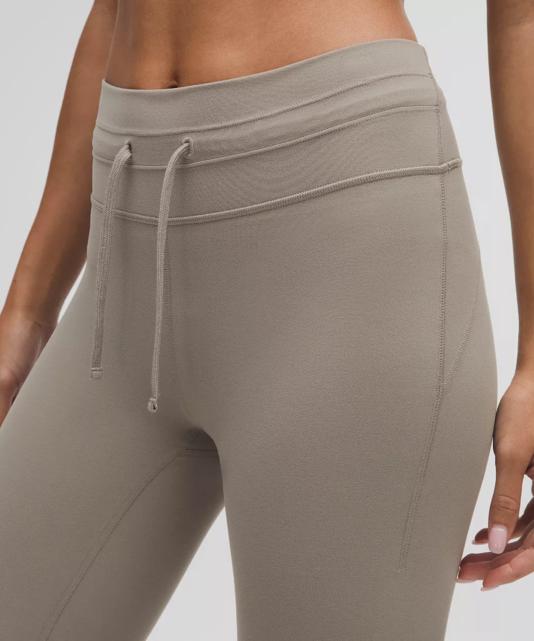 Beige leggings with a drawstring waistband on a neutral background