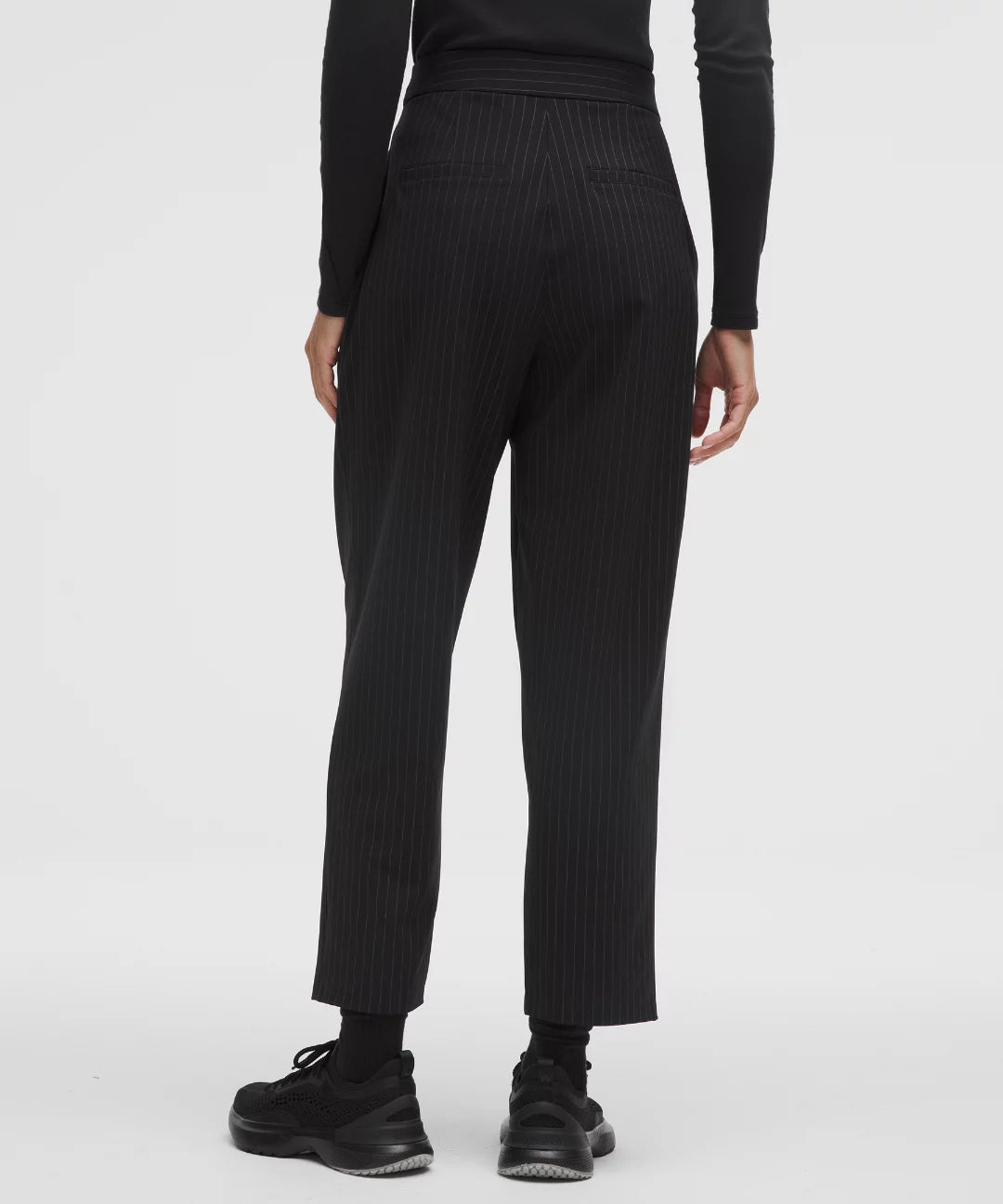 Person wearing black ribbed knit pants on a white background