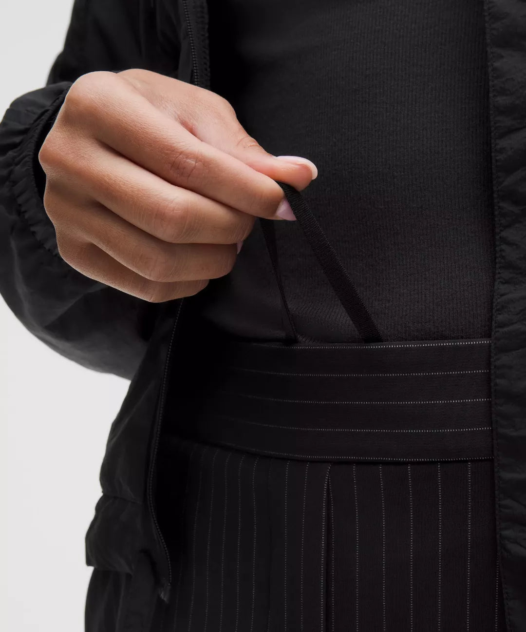 Person wearing a black outfit with a close-up of a hand adjusting a strap.