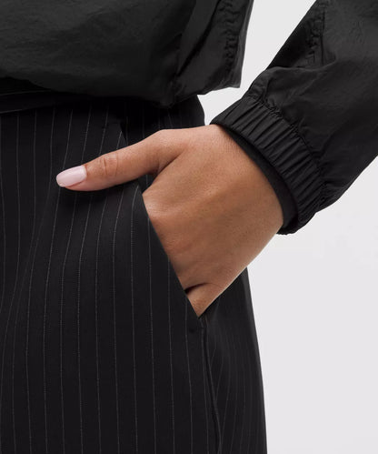 Hand in a black pinstripe suit pocket on a light gray background
