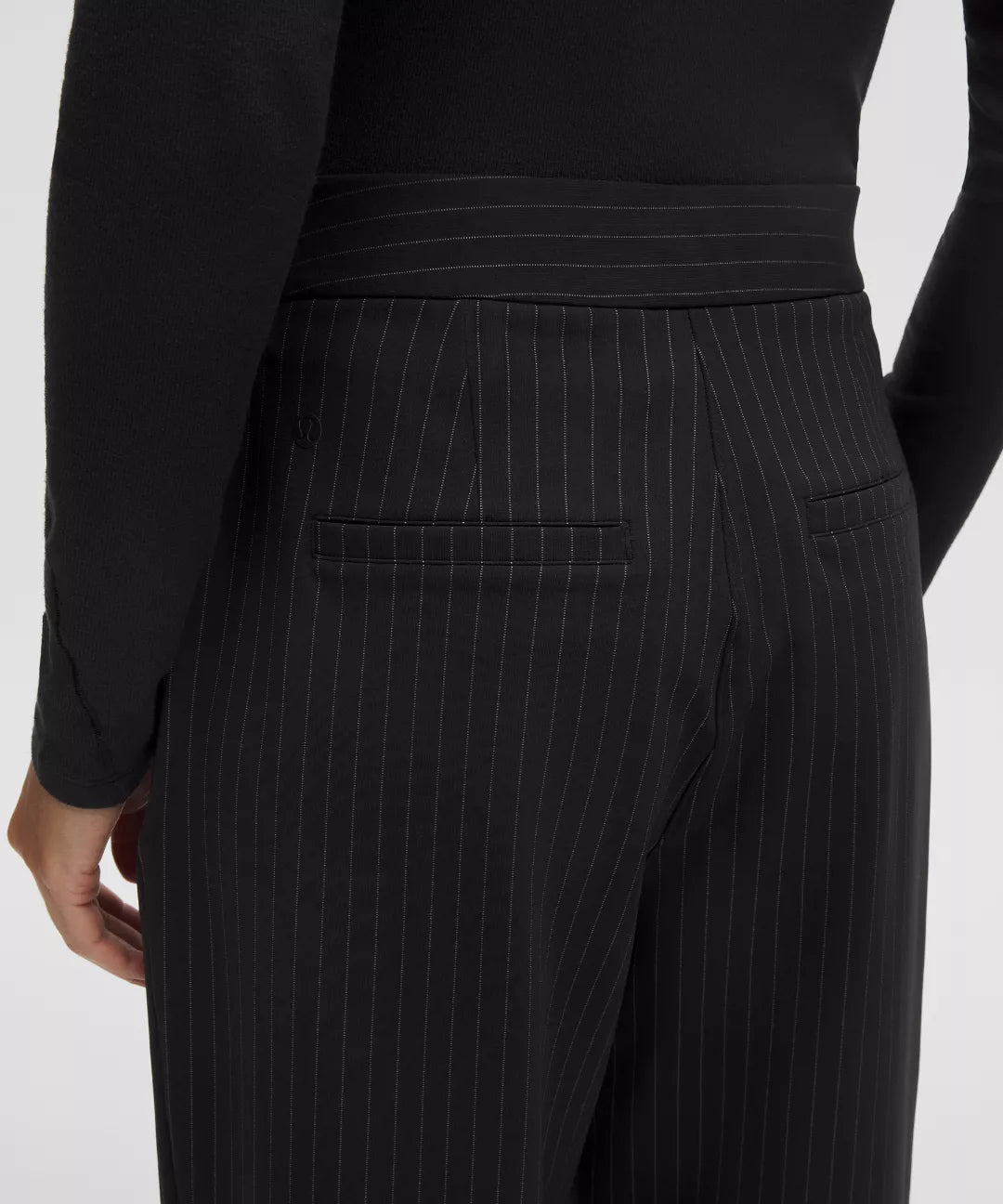 Black pinstripe pants worn by a person on a white background
