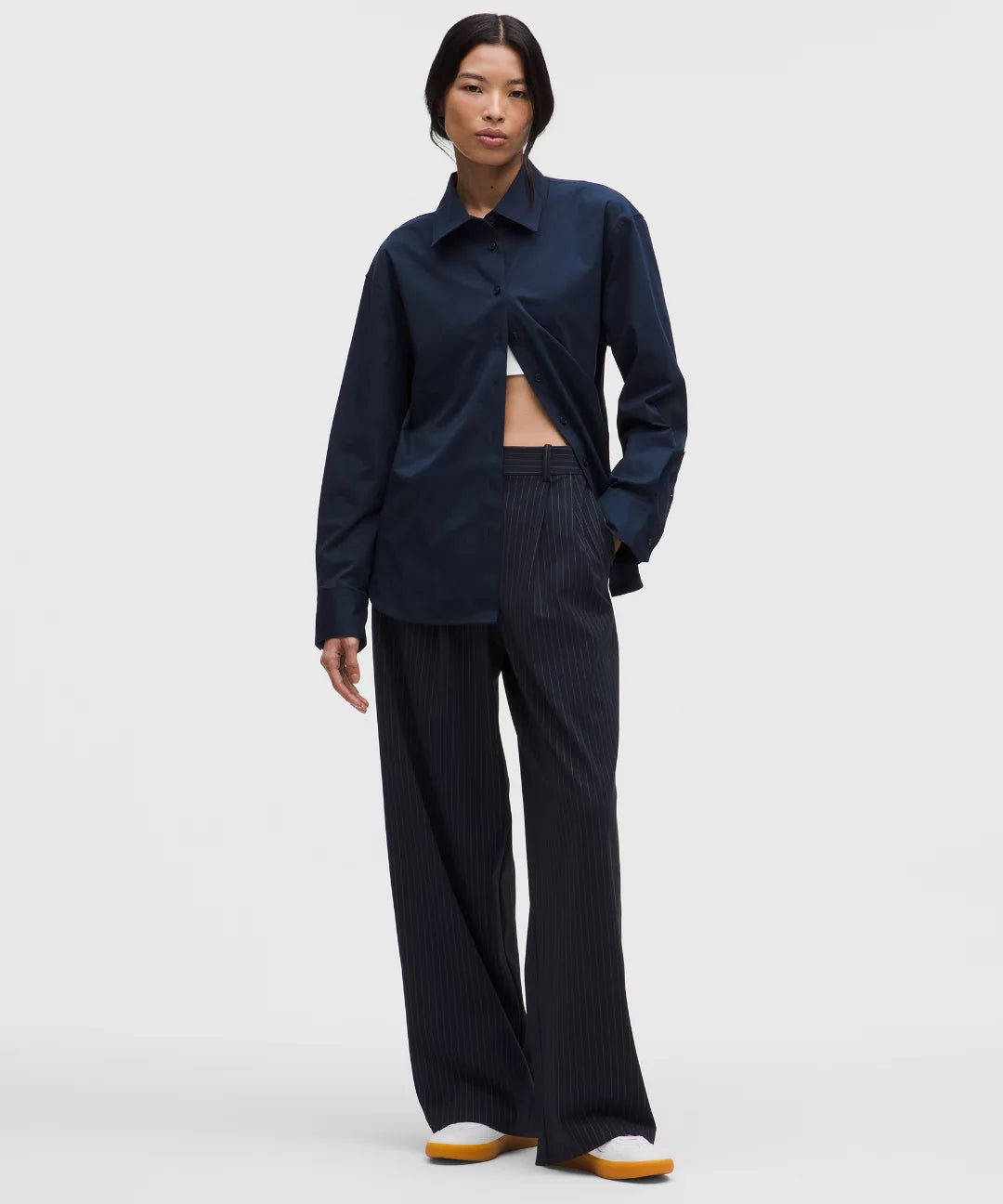 Person wearing a navy blue shirt and wide-leg pants on a white background
