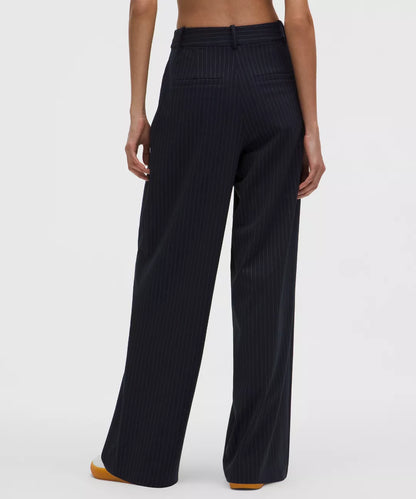 Navy pinstripe pants worn by a model on a white background